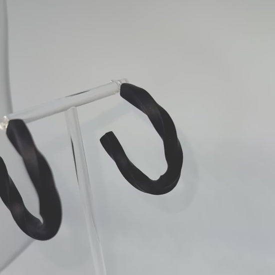 Black polymer clay twisted hoop earrings on a display stand – handmade bespoke earrings from an artisan jewellery store, part of a handcrafted clay jewellery collection perfect for gifting or everyday wearable art.
